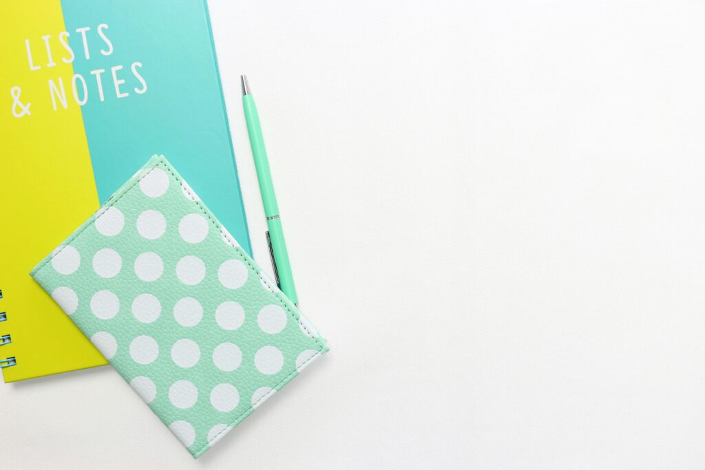 Two blue and yellow notebooks and a pen - for writing lists of what you really need for a new baby.