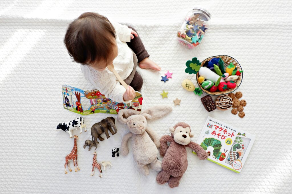 A baby sits surrounded by several toys - lovely to have but not what you really need for a new baby
