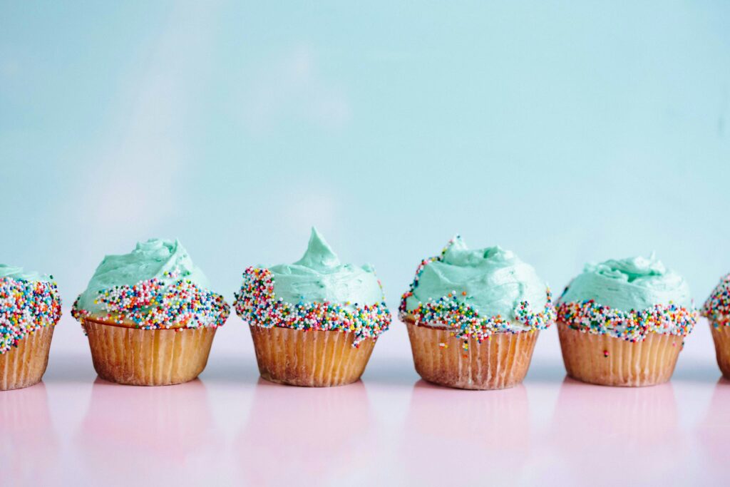 A row of cupcakes with blue icing and sprinkles