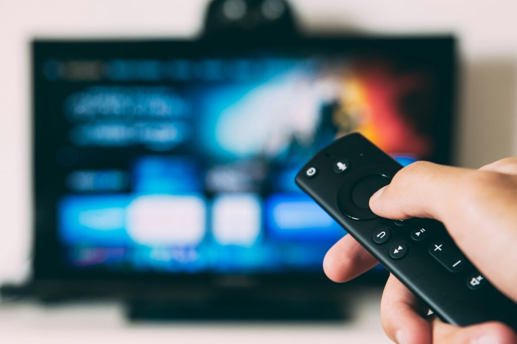 A remote control in the foreground turning on a TV in the background